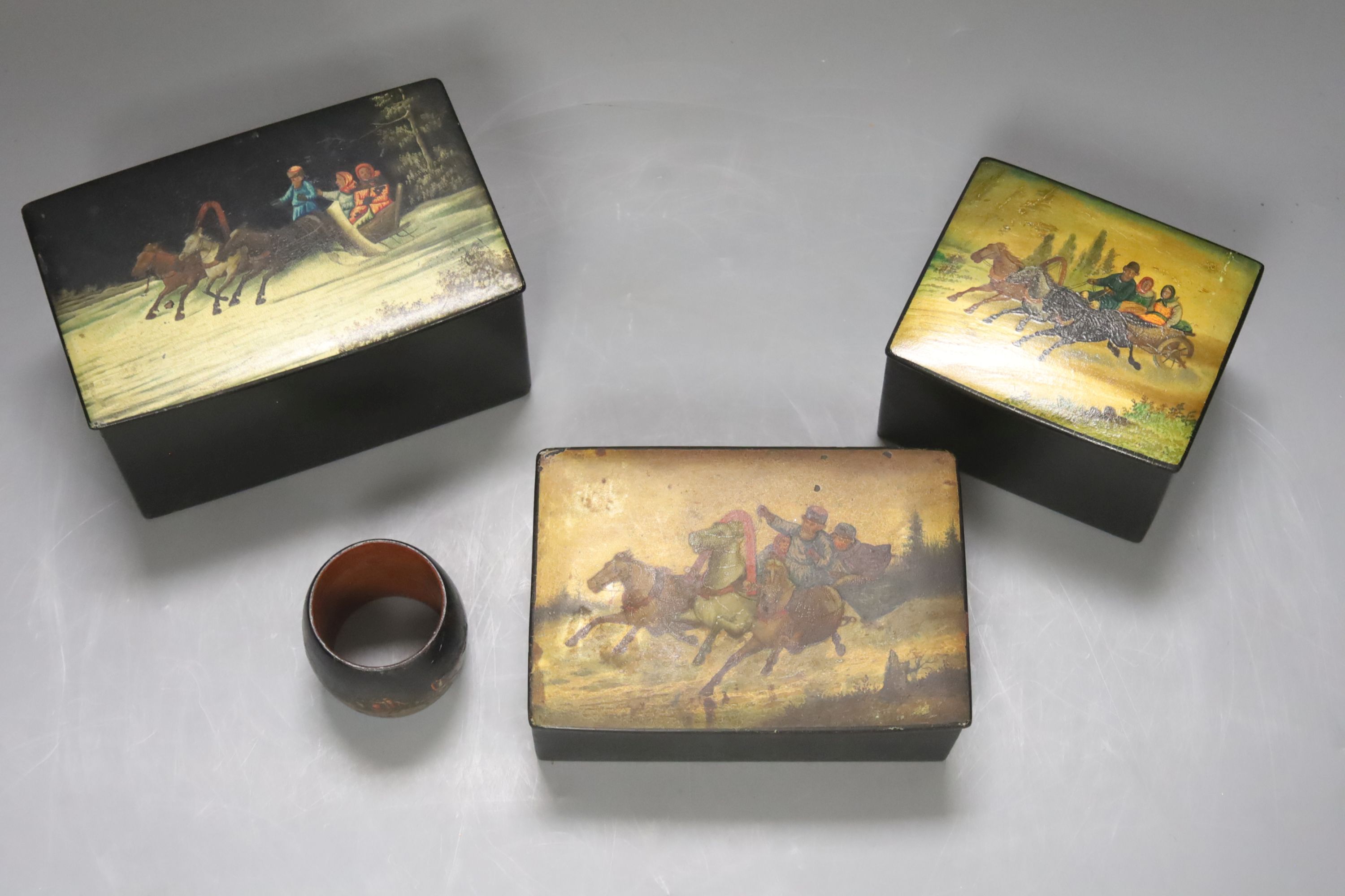 Three Russian lacquer ‘troika’ boxes, largest 13.5cm and a napkin ring